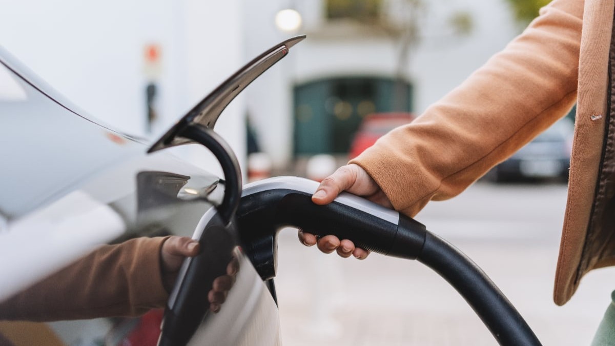 Un bărbat care încarcă o mașină electrică.