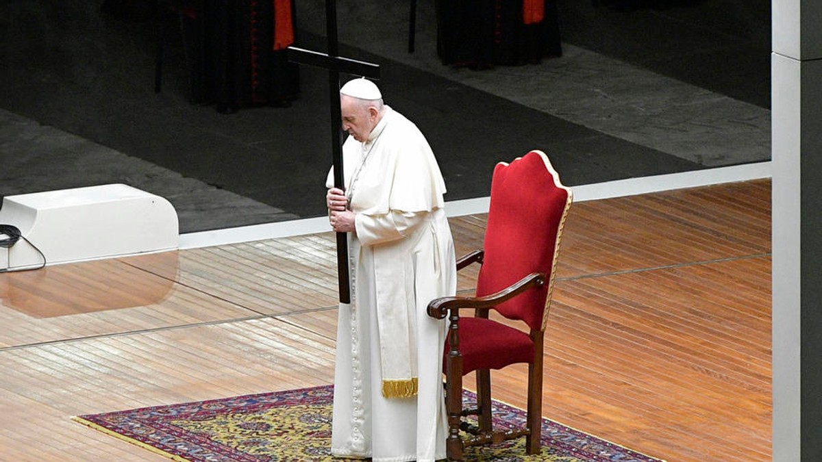 Papa Francisc în depărtare, se asează pe scaun în timpul unei procesiuni în Piața Sfântul Petru