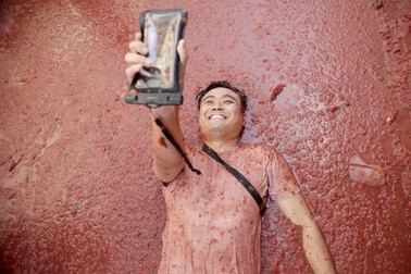 Un participant își face un selfie în timpul festivalului La Tomatina din Bunol, estul Spaniei, pe 31 august 2022. Ca în fiecare an, în ultima miercuri din august, mii de oameni vizitează micul sat Bunol pentru participă la Tomatina, o bătălie în care tone de roșii coapte sunt folosite pentru a se arunca unul în celălalt. În jur de 130.000 de kilograme de roșii vor fi aruncate.