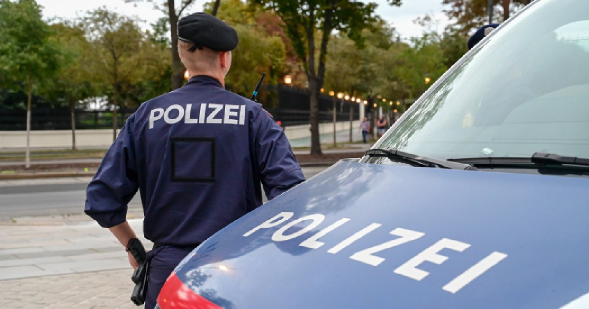 Polițist din Austria lângă o mașină de poliție. Polițist în uniformă, în patrulă pe stradă.