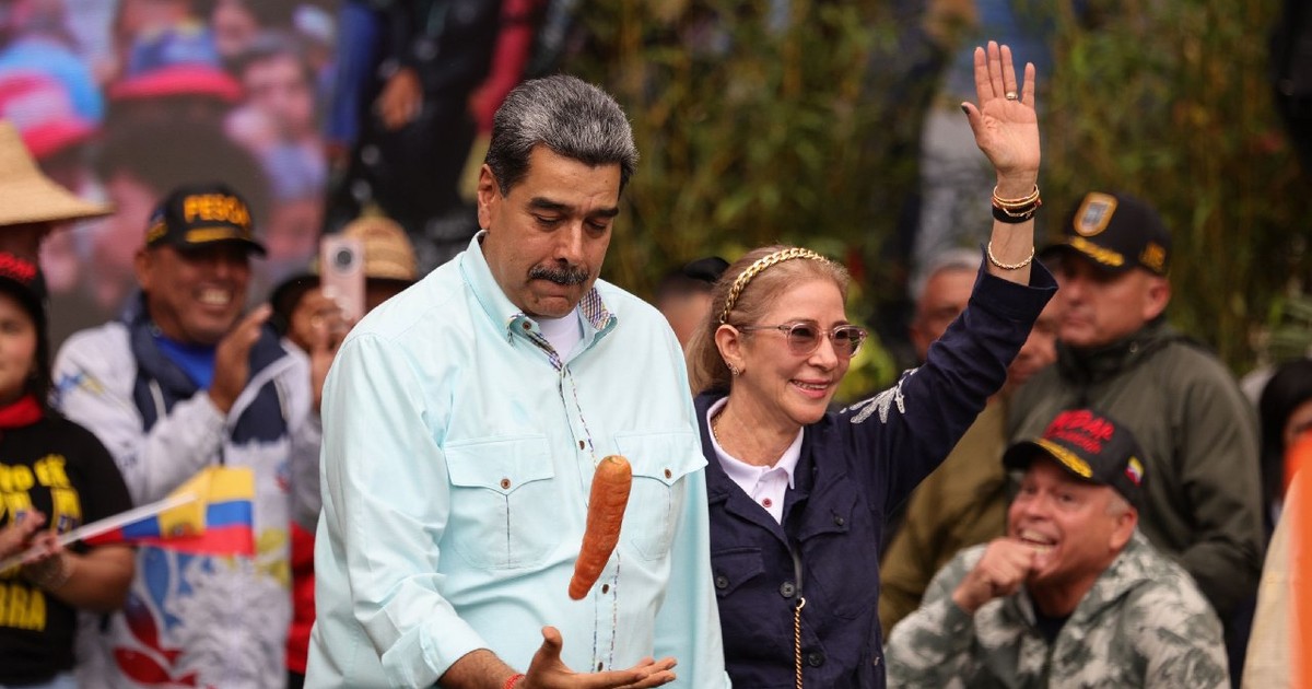 10 decembrie 2025, Venezuela, Caracas: Președintele venezuelean Nicolas Maduro se joacă cu un morcov lângă soția sa, Cilia Flores (dreapta), în timpul unui miting organizat pentru a comemora bătălia de la Santa Ines.