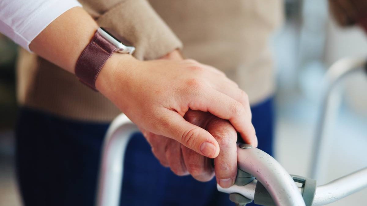 Mâini, îngrijitor și pacient în vârstă cu walker pentru suport de mobilitate, ghidare de mers pe jos și vindecare la pensionare. Casă de îngrijire medicală, asistentă și persoană în vârstă în asistență pentru servicii de asistență medicală și ajuto