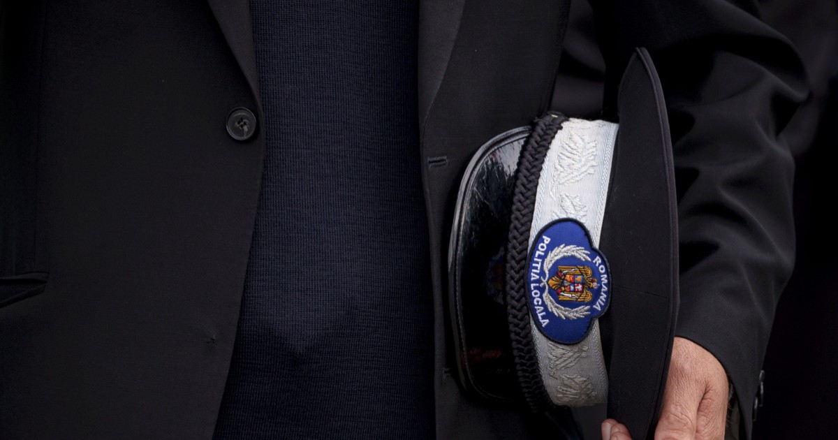 Polițist local, în timp ce își ține cascheta în mână
