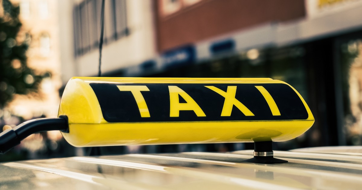 Un semn galben pe care scrie TAXI, montat pe plafonul unui vehicul.