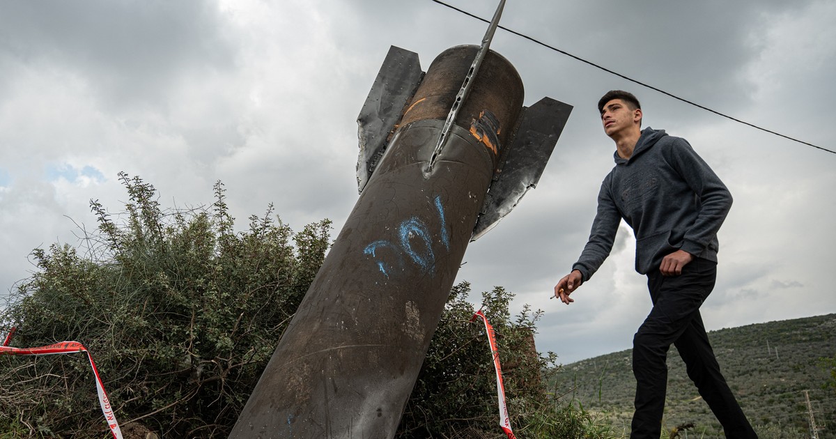 Un băiat trece cu o țigară în mână pe lângă o rachetă iraniană căzută în Palestina.