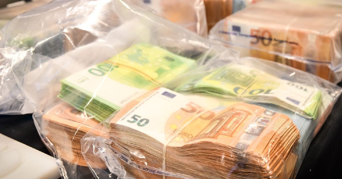 Imaginea prezintă mai multe teancuri de bani, bancnote de 50 și 100 de euro, în pungi din plastic, așezate pe o masă.