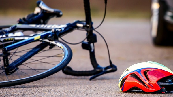 O bicicletă căzută pe jos. Lângă aceasta se află o caschetă colorată