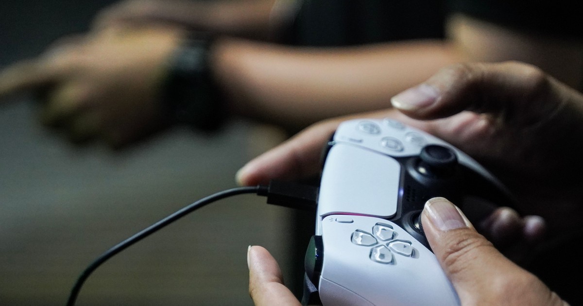 Un controller de PlayStation 5, în mâna unui gamer.