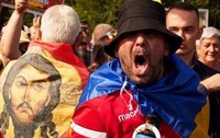 O imagine cu fața lui Isus pe un steag purtat pe spate de un protestatar, langa un al protestatar care tip la protestul fermierilor din Piața Victoriei, de pe 15 septembrie