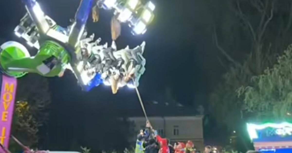 Captura video, imagini de noapte, copii blocati intr-un carusel luminos, sunt cu capul in jos, mai multi pompieri trag cu o sfoara de bratele caruselului