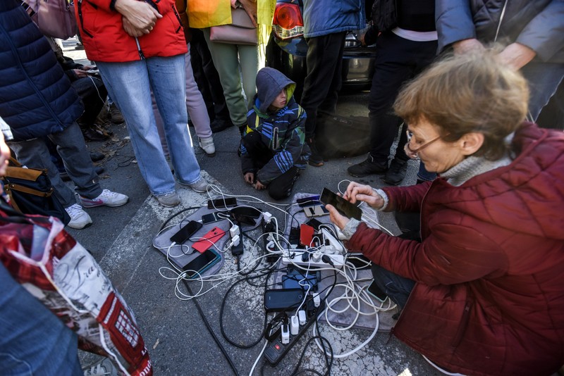 Locuitorii din Herson își încarcă telefoanele mobile la un generator amplasat pe stradă, în noiembrie 2022. Foto: EPA