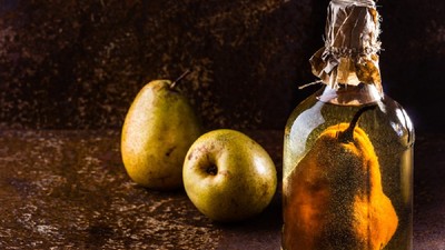 Pară într-o sticlă cu alcool şi alte două pere lângă