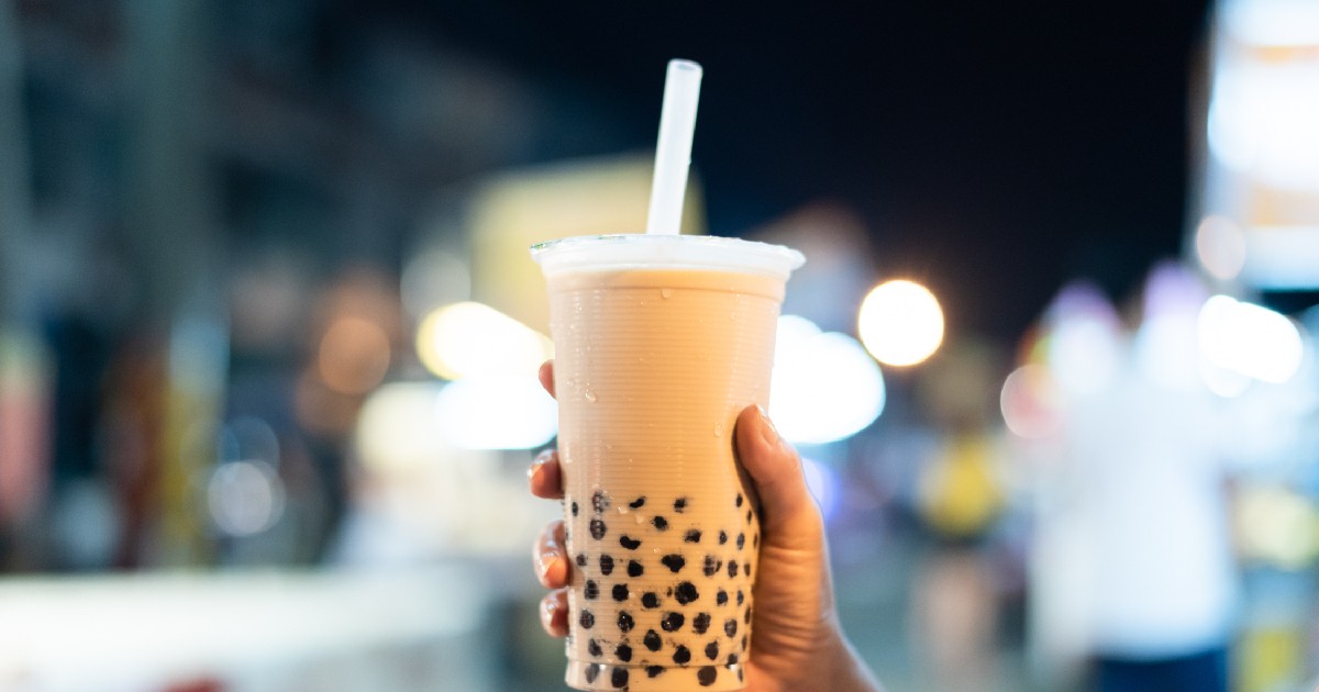 O persoană ține în mână un pahar cu bubble tea