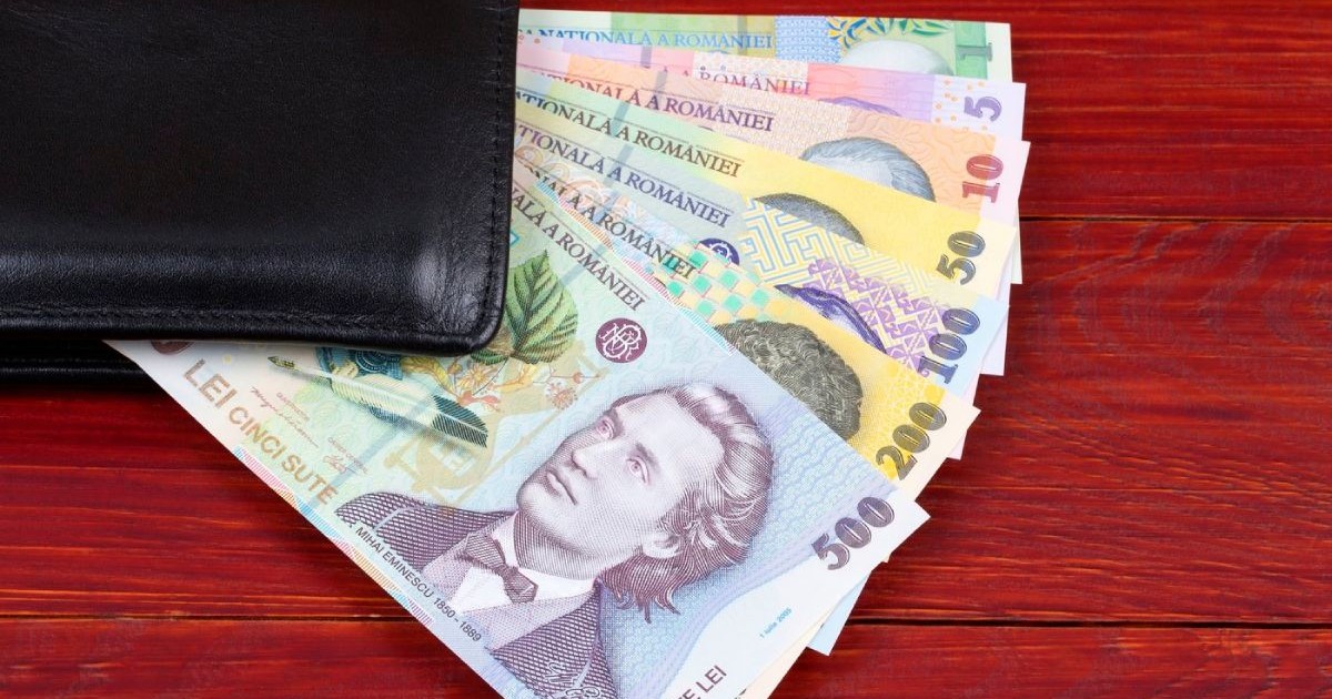 Bancnote de 500, 200, 100, 50, 10, 5 și 1 leu aranjate în evantai, într-un portofel negru pe o masă de lemn