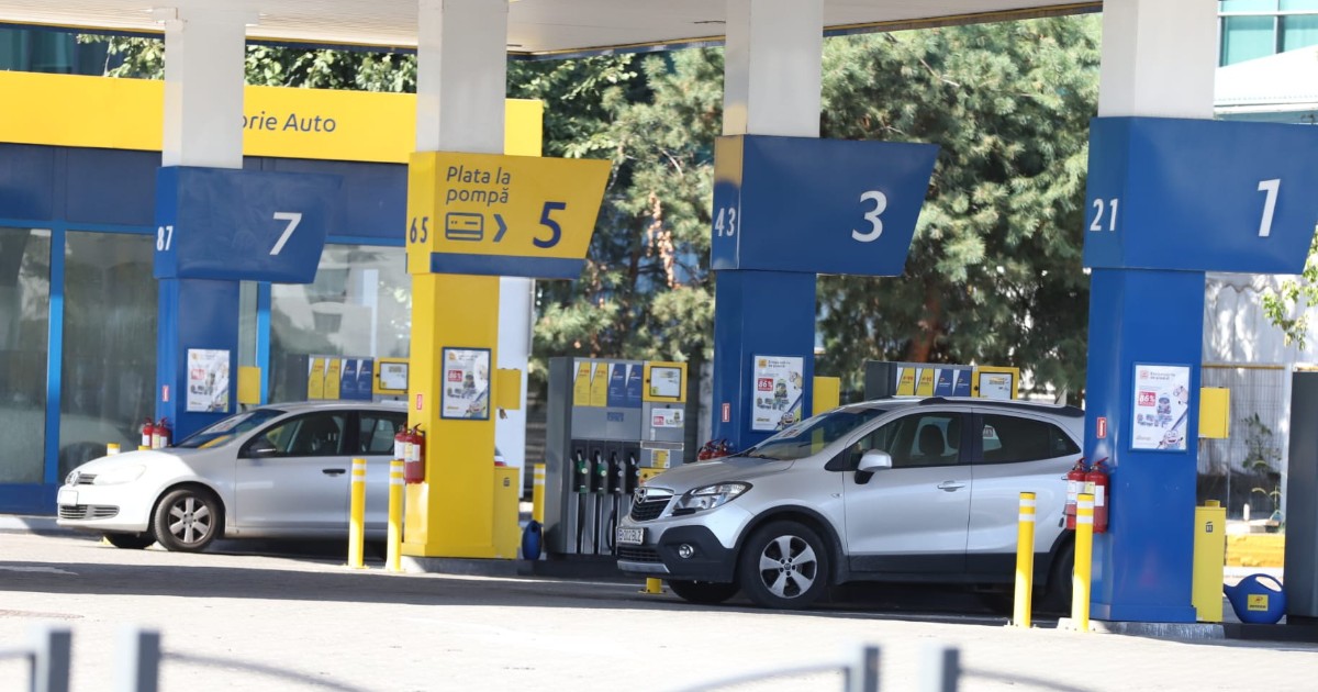 Imaginea prezintă o stație de carburanți cu mai multe pompe numerotate, unde sunt parcate două autoturisme pentru alimentat.