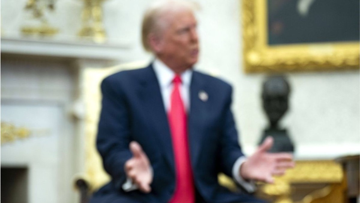 Fotografie în ceață cu Donald Trump. În prim-plan, un suport de cană din aur.