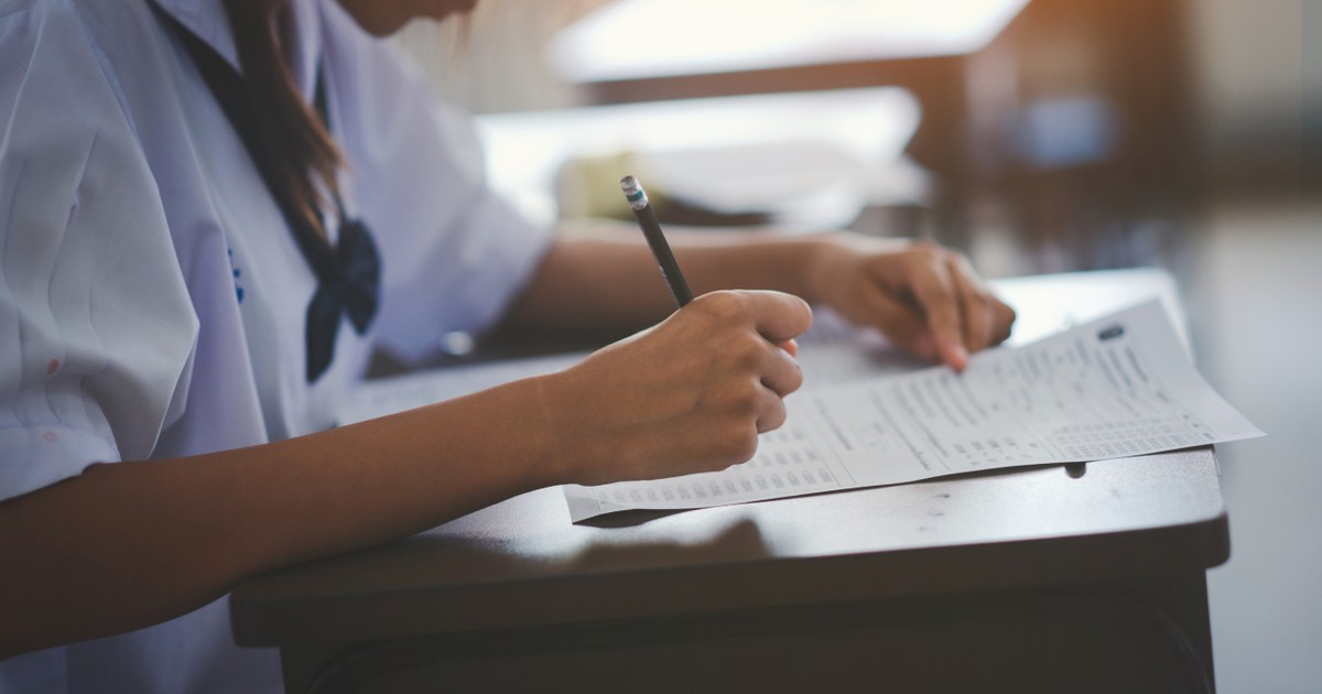 Elevii stau pe scaune în sala de examen sau în clasă, purtând uniforme