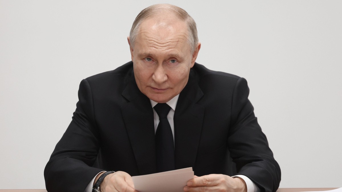 Vladimir Putin stă la birou, îmbrăcat într-un costum negru. Are niște documente în mâini Foto: Hepta