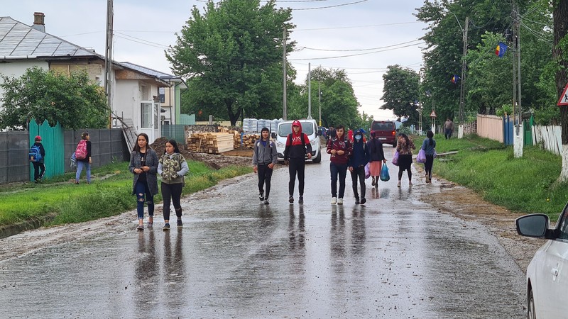Străzile din sat, cu copiii care se întorc de la școală