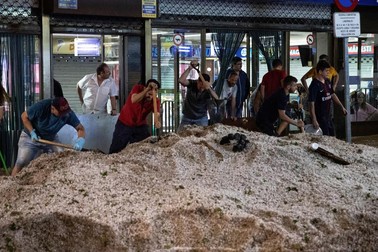 Mai mulți oameni încearcă să îndepărteze grămezile de grindină de pe străzile din Madrid | Foto: EPA