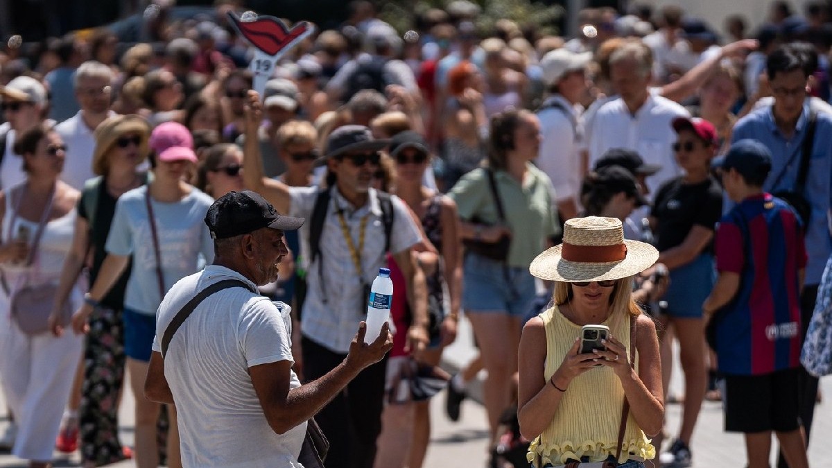 Turiștii vizitează Sagrada Familia protejându-se cu sticle de apă, evantaie, pălării și ventilatoare portabile în timpul unei valuri de căldură în Barcelona, Spania, pe 15 august 2025.