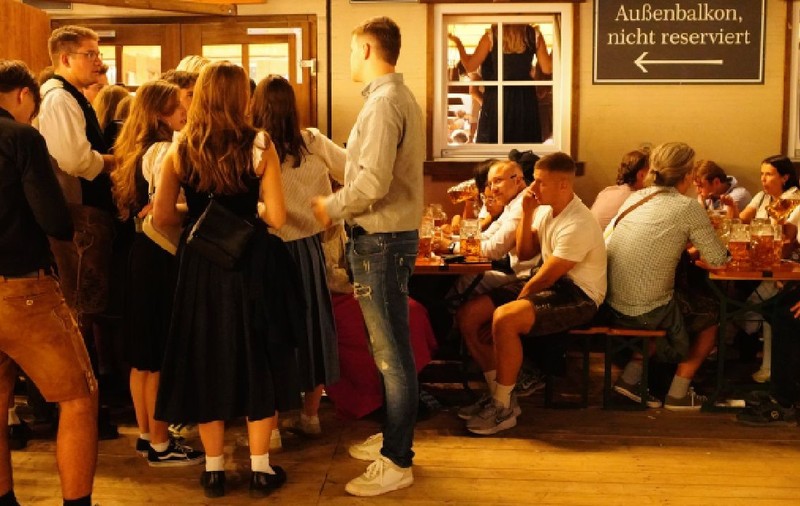 Oamenii se distrează la Oktoberfest 2026. În imagine, mai multe grupuri de tineri, băieți și fete, în fața unui local