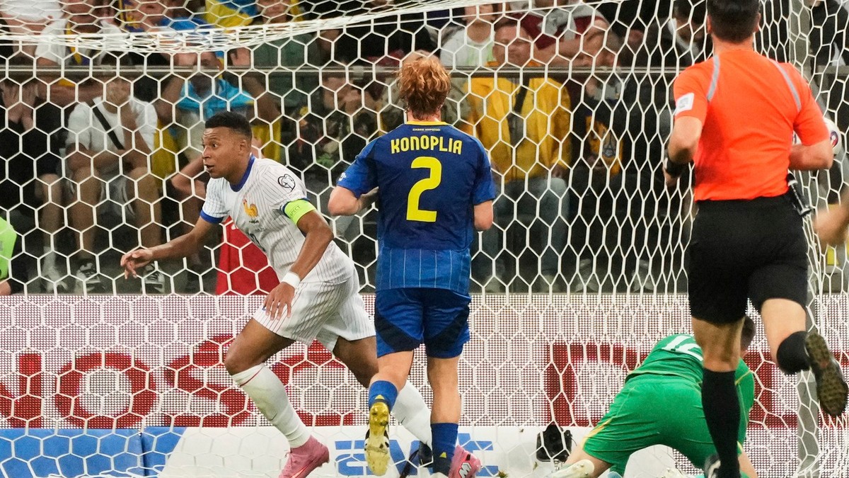 Aatacantul francez Kylian Mbappe, stânga, intr-un echipament alb cu dungi albastre,sărbătorește după ce a marcat al doilea gol al echipei sale în timpul meciului de calificare la Cupa Mondială FIFA 2026 dintre Ucraina și Franța, disputat vineri la Tarczynski Arena din Wroclav, Polonia. In imagine, cu spatele, se vede fotbalistul ucrainean Konoplya