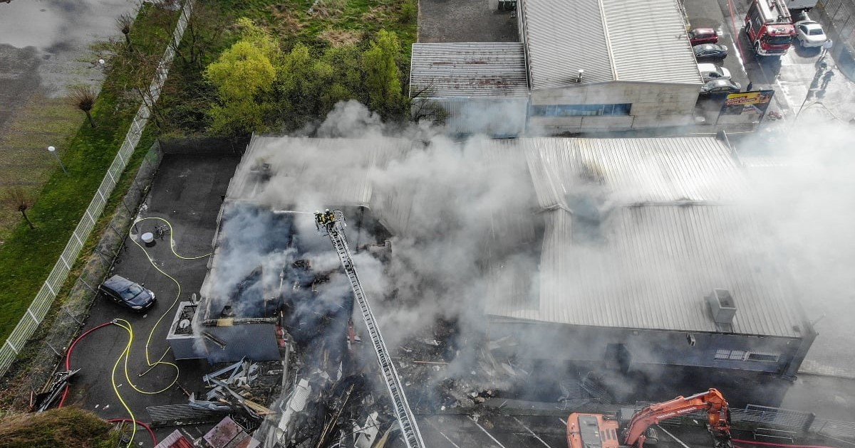 Imagine văzută de sus cu urmările unui incendiu. Coloane mari de fum se ridică deasupra întregii structuri.