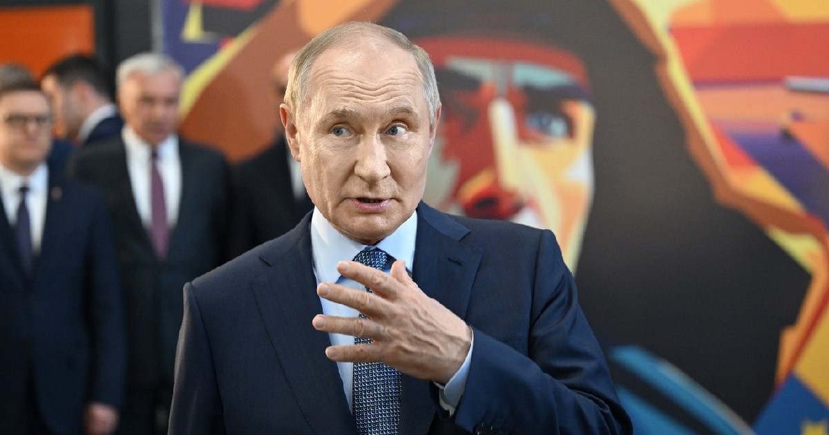 Președintele Rusiei, Vladimir Putin, îmbrăcat într-un sacou negru, cu o cămașă albă și o cravată bleumarin gesticulează, ținând mâna stânga în fața nodului cravatei sale în timpul unei vizite de lucru la combinatul siderurgic Magnitogorsk, în care inspectează un atelier de produse din industria construcțiilor de mașini, 17 iulie 2025