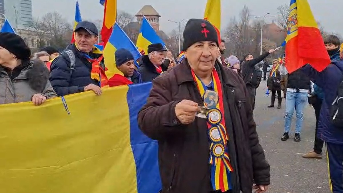 un bătrân este surprins tămâind mulțimea, în timp ce în jurul lui se aud scandările „Jandarmeria apără hoția!”.