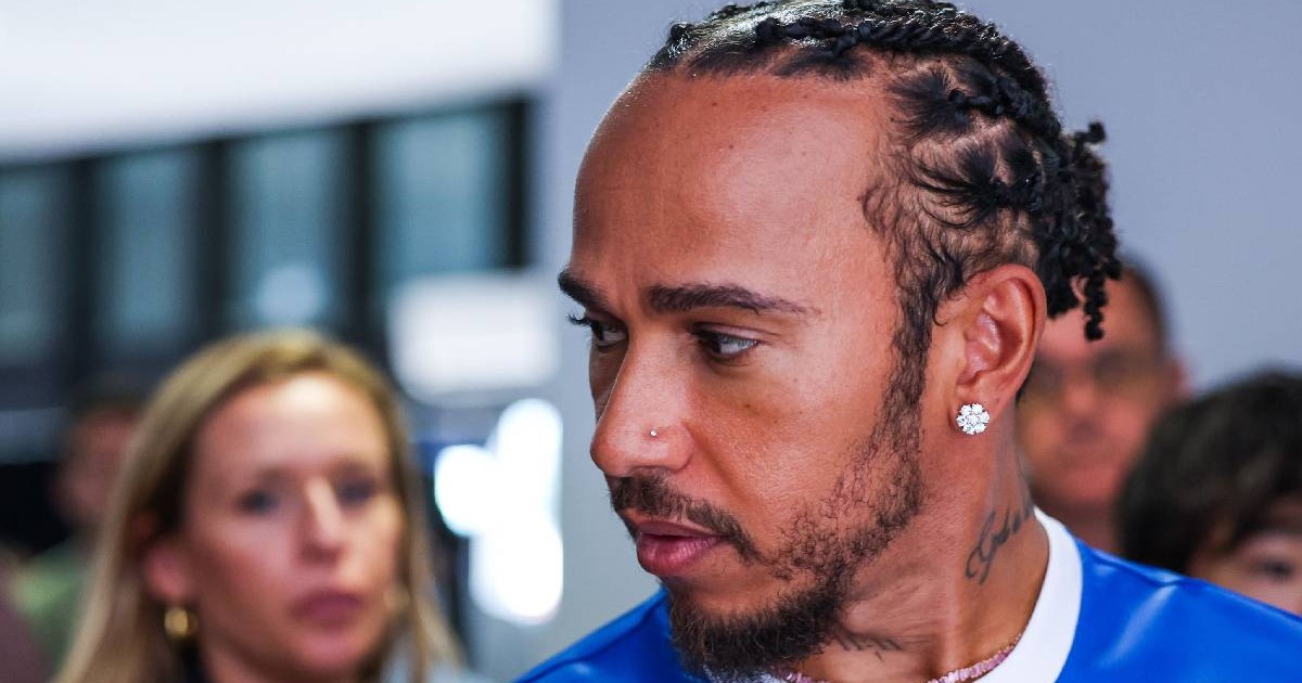 Lewis Hamilton, îmbrăcat într-un tricou albastru în prim plan, privește într-o parte
