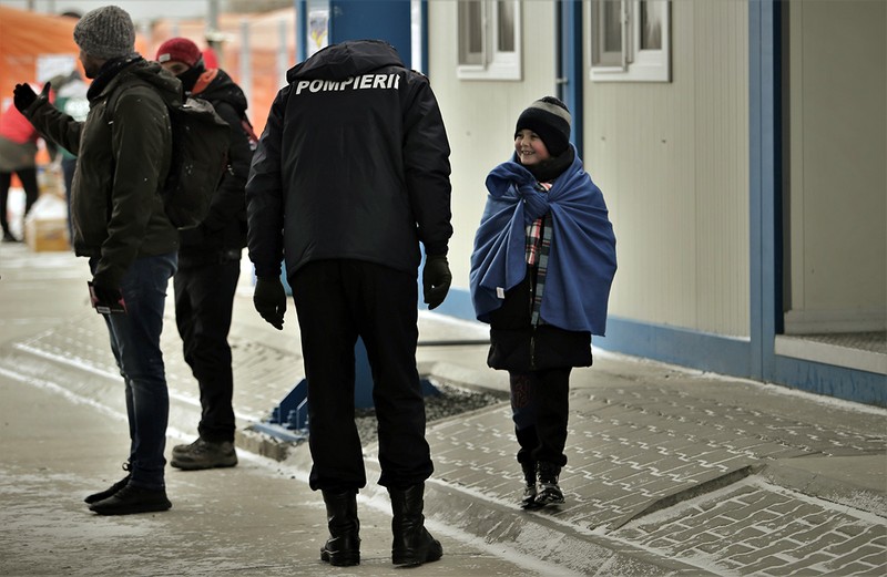 Un pompier român discută cu un copil refugiat