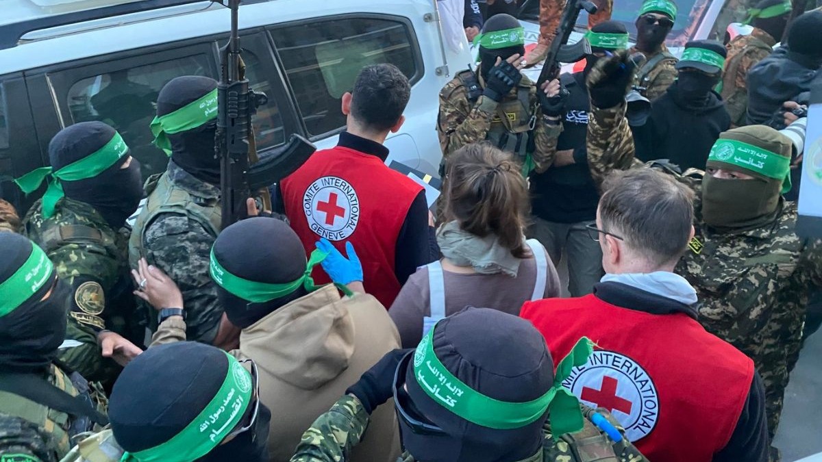 mai mulți palestinieni adunați lângă locul predării prizonierilor israelieni către reprezentanților Crucea Roșie, care poartă veste cu însemnele organizației