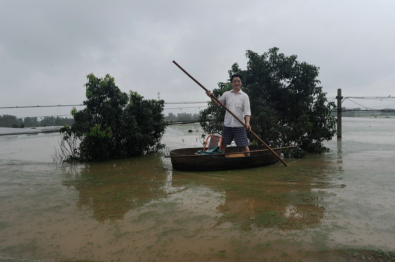 ANHUI, CHINA - JULY 03: A man rows a raft in a flooded village in Shucheng county on July 03, 2016 in Anhui, China. The flooding broke an embankment of Fengle River Saturday afternoon, forcing evacuation of four villages. PHOTOGRAPH BY Feature China / Barcroft Images London-T:+44 207 033 1031 E:hello@barcroftmedia.com - New York-T:+1 212 796 2458 E:hello@barcroftusa.com - New Delhi-T:+91 11 4053 2429 E:hello@barcroftindia.com www.barcroftimages.com *** Local Caption *** 02537428