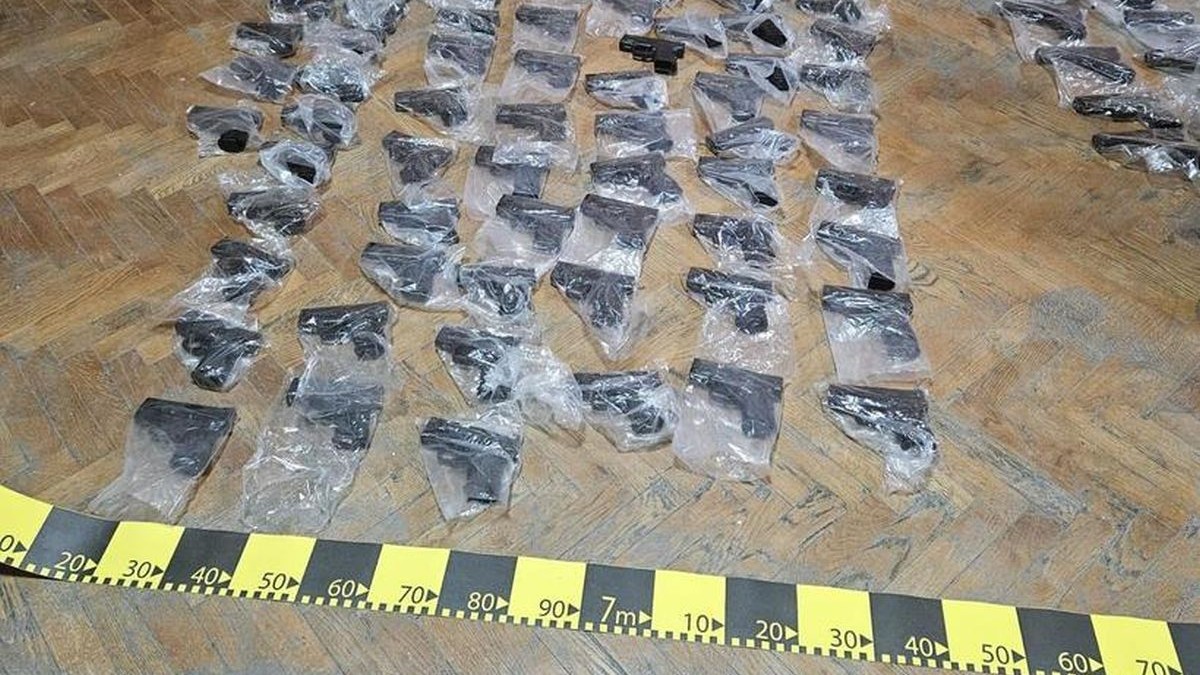 Mai multe pistoale negre învelite fiecare în pungă din plastic transparentă sunt puse pe jos, pe parchet, după ce au fost descoperite de poliția de frontieră din Calafat, România, 6 noiembrie 2025