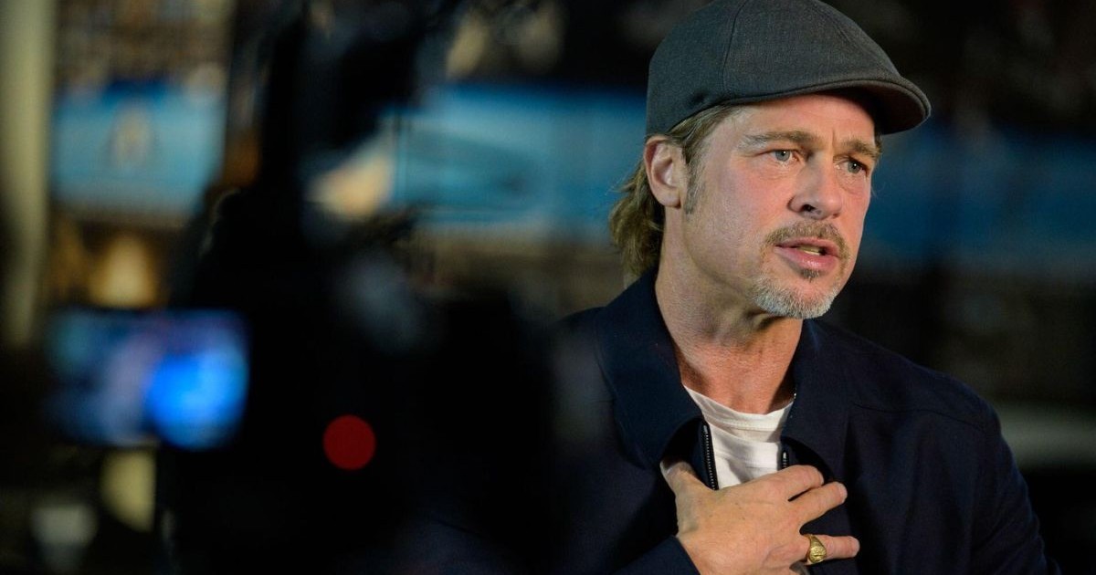 Actorul Brad Pitt, îmbrăcat cu tricou alb, sacou negru și șapcă, își pune mâna pe piept, când participă la o conferință în direct cu astronautul NASA Nick Hague de la Centrul de Operațiuni Spațiale de la sediul NASA, pe 16 septembrie 2019