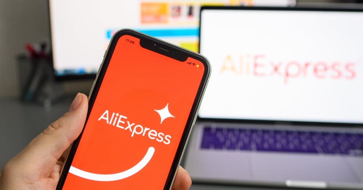 Un telefon pe ecranul căruia scrie AliExpress. În fundal se observă un laptop pe care scrie AliExpress