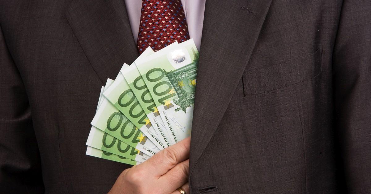 Un bărbat îmbrăcat în costum ia mită și bagă banii în costum.