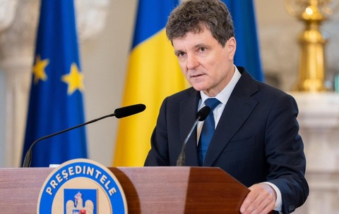 Imaginea îl prezintă pe Nicușor Dan vorbind de la o tribună oficială, având în fundal steagurile României și Uniunii Europene.