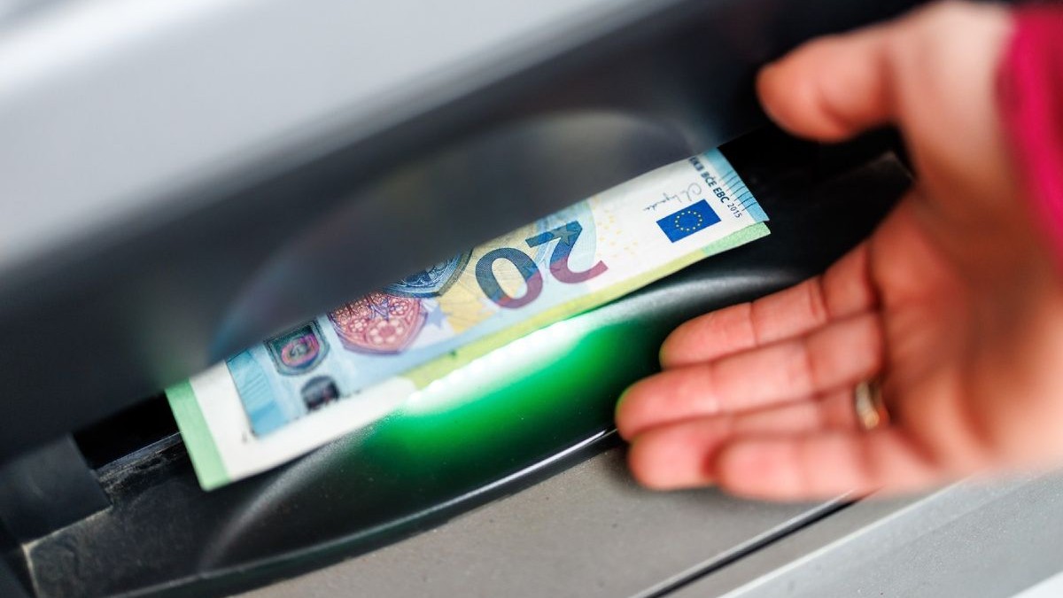 O femeie scoate o bancnotă de 20 de euro dintr-un bancomat, pe 29 mai 2025, pe o stradă din Munchen, Germania
