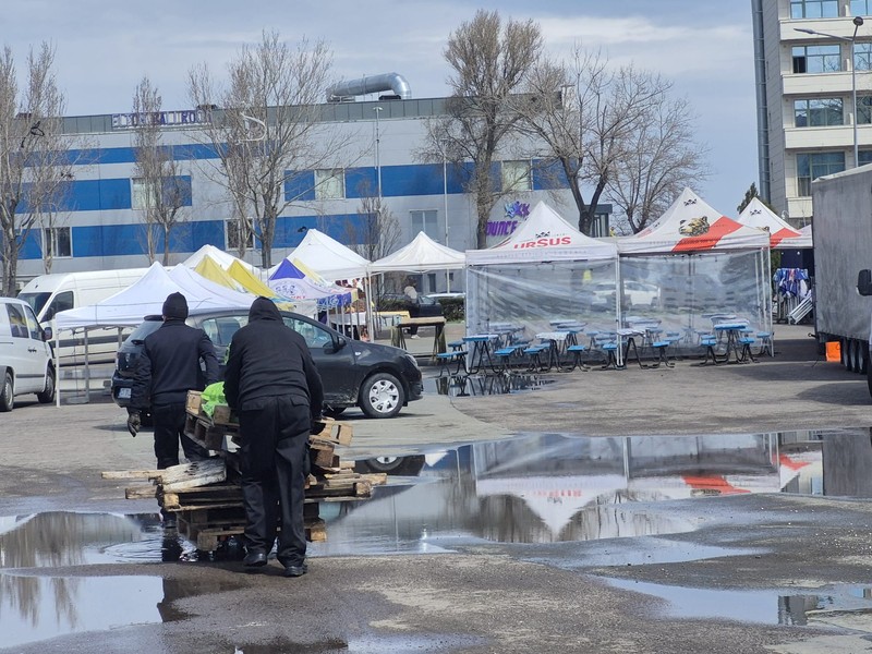 Două persoane cară mai mulți paleți.