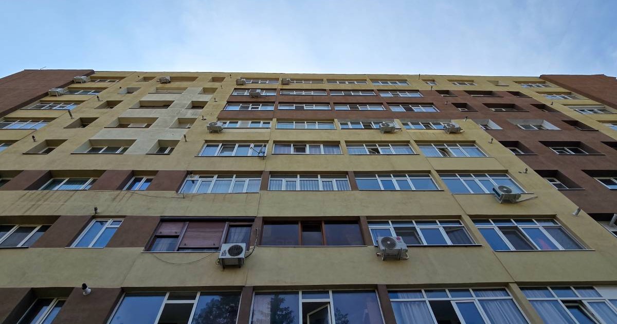 Exteriosrul unui bloc pe care se vad mai multe aparate de aer condiționat, imagine de jos, cerul albastru deasupra