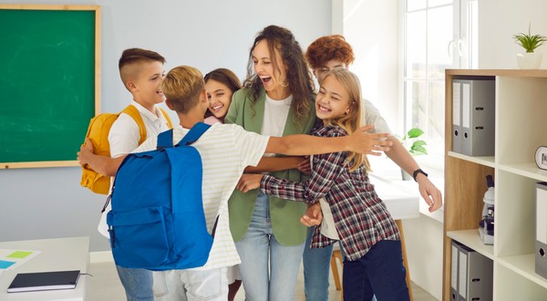 Elevi fericiți, alături de învățătoarea lor. Poză cu caracter ilustrativ. Foto: Shutterstock