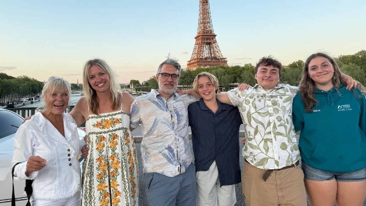 O familie cu 4 copii adolescenți si pe fundal Turnul Eiffel