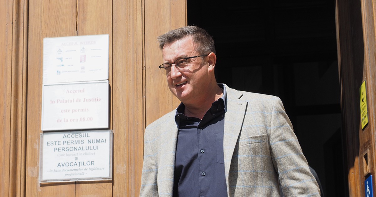 Un barbat in sacou gri iese din cladirea tribunalului