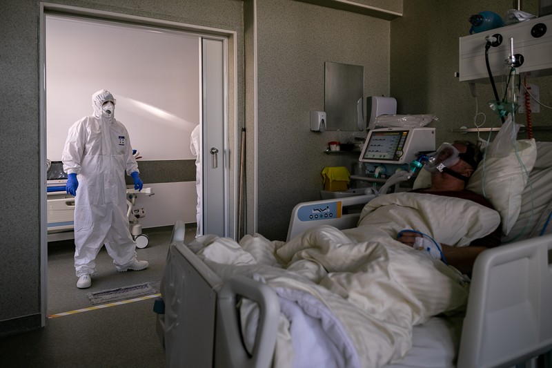 Un pacient cu mască mare de oxigen este supravegheat de un medic