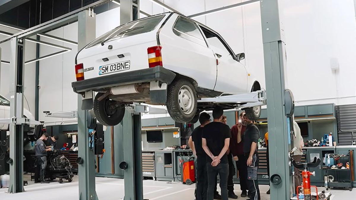 Patru mecanici auto studiază o mașină Oltcit într-un atelier auto, octombrie 2025
