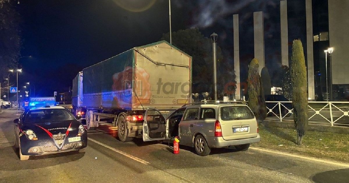 Fotografie cu o scenă nocturnă pe șosea, care arată un accident între un autoturism și un camion, lângă o mașină de poliție.
