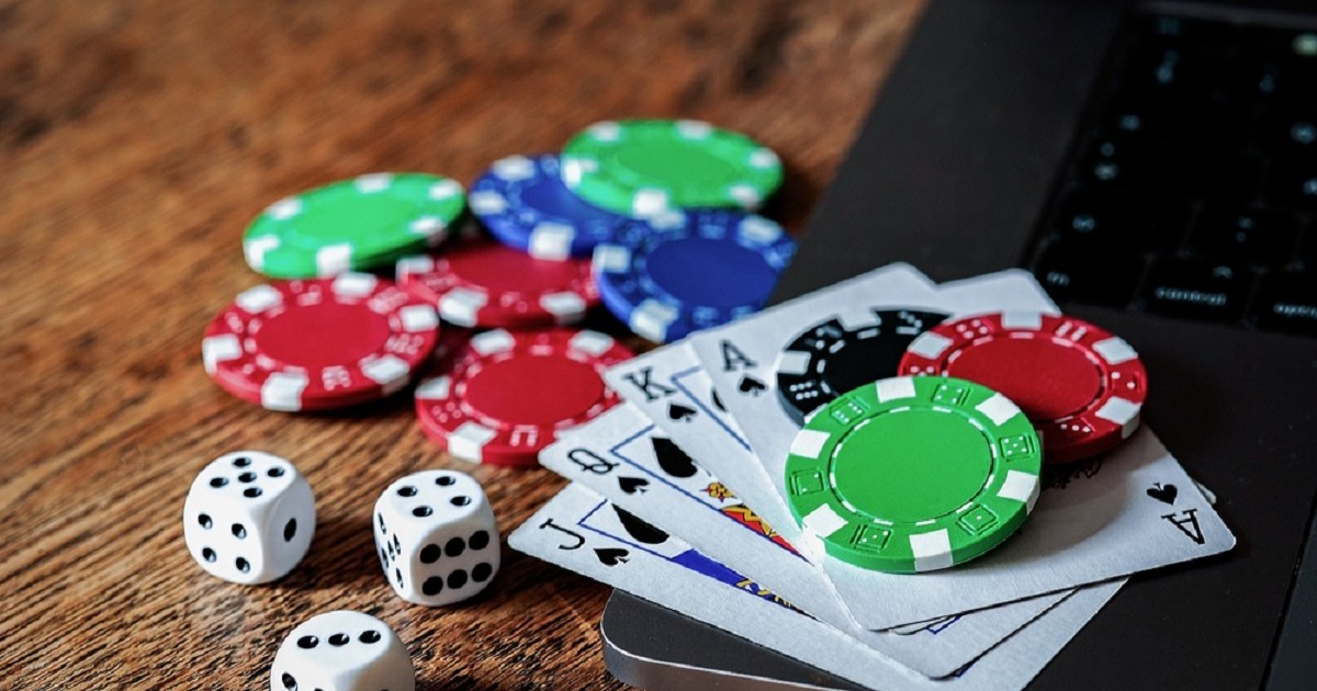 Pe o masă sunt puse cateva jetoane de poker, zaruri si carti de joc aranjate pe un telefon negru
