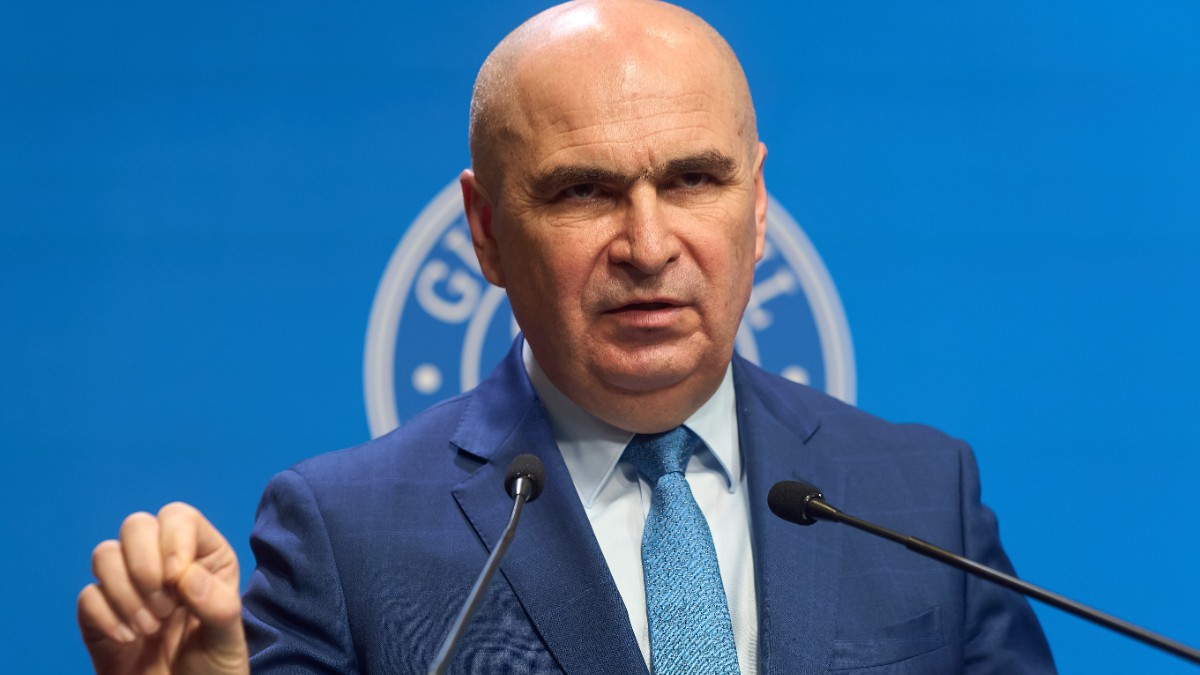 Ilie Boloajn îmbrăcat în costum albastru, gesticulând în fața unui microfon